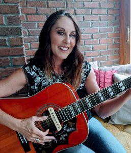 Lana White country singer playing her guitar in posed photo. 